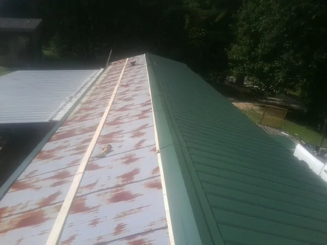 Old rusted panels beside newly installed green metal roofing — Wind Damage Roof Repair by Roofing Brothers in Clairton