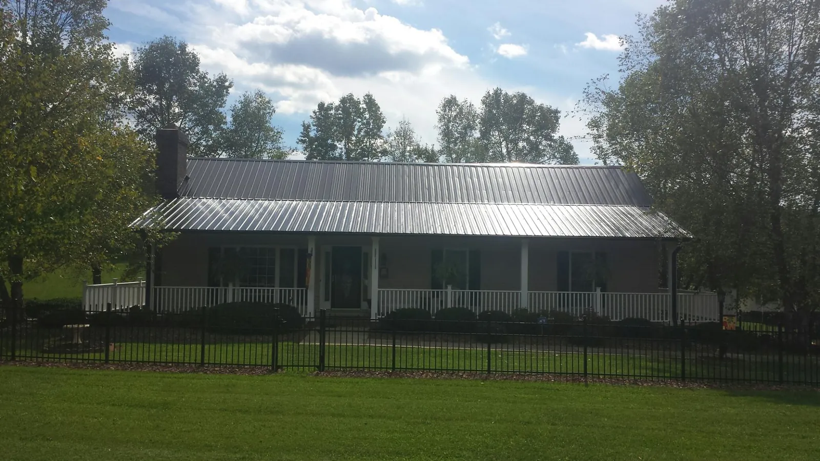 Gray metal roof on a brick ranch with a full width front porch — Gutter Guard Installation work by our crew in Clairton